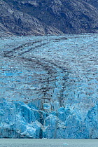 Black streaks (medial moraine) in the Dawes Glacier are indicative of two glaciers colliding or joining together. Alaska, July 2011