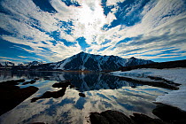 Sky and clouds reflected in melted Fjord in Svalbard, Sptizbergen, Norway, July 2009, Taken on location for the BBC series, Frozen Planet.