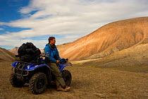 Director, Jeff Wilson, on an all-terrain-vehicle searching for Arctic Wolves, Ellesmere Island , Nunavut, Canada, June 2008. Taken on location for the BBC series, Frozen Planet.