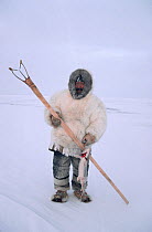 Inuit hunter with Kakivak (fishing spear) and caught fish, Igloolik, Nunavut, Canada, 1993. 40 BELOW bookplate.