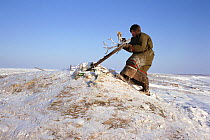 Nenets man placing offering of Reindeer / Caribou antlers at sacred site on the Gydan Peninsula, Northwest Siberia, 2000. 40 BELOW bookplate.