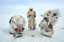 Nenets men checking fishing net set under ice on lake in the Gydan Peninsula. Western Siberia, Russia, 2000. 40 BELOW bookplate.