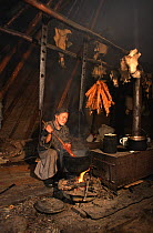 Nenets woman cooking fish inside her tent at summer fishing camp. Yamal, Western Siberia, Russia, 2000. 40 BELOW bookplate.