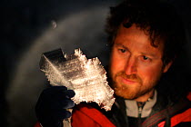 BBC producer Chadden Hunter looking at the incredible ice crystal formations inside volcanic ice caves below Mount Erebus, Antarctica. Taken on location for BBC Frozen Planet series, 2009