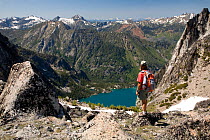 Hiker looking down on Colchuck Lake from Aasgard Pass in the Alpine Lakes Wilderness, Washington, USA, July 2009. Model released