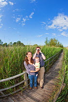 Family, couple with baby, birdwatching in reedbeds at Westhay SWT reserve, Somerset Levels, Somerset, England, UK, June 2011 Model released
