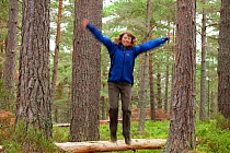 Woman aged 35-45 years jumping off log in Abernethy Forest, Cairngorms National Park, Scotland, UK, August 2010, Model released