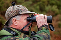 Deer stalker scanning for deer with binoculars, Assynt Foundation, Glencansip Estate, Assynt, Sutherland, NW Scotland, UK, January 2011. Model released