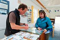 Woman purchasing stamps at Tanera More post office and tea room, Coigach and Assynt, Sutherland, Scotland, UK, June 2011