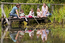 Children and mothers pond dipping and enjoying pond environment at Little Bradley Ponds, Bovey Tracy, Devon, UK. July 2011. Model released.