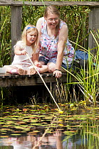 Child and mother pond dipping and enjoying pond environment at Little Bradley Ponds, Bovey Tracy, Devon, UK. July 2011. Model released