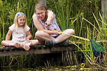 Child and mother pond dipping and enjoying pond environment at Little Bradley Ponds, Bovey Tracy, Devon, UK. July 2011. (Model released).