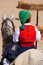 Back of a traditionally dressed cowboy mounted on his horse, during the Festa do Colete Encarnado (Red Waistcoat Festival), a bull running festival, in the bullring of Vila Franca de Xira, District of...