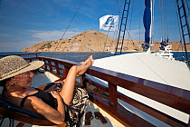 Woman relaxing on the sun deck of a yacht, Indonesia, August 2009. Model released. No property release.