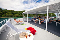 Passengers relaxing on sun deck of yacht, Palau, Indonesia, July 2010. No release.