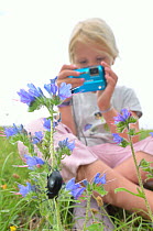 Child in garden photographing flowers and insects. France, Europe, August. Model released.