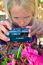 Child photographing a Praying Mantis (Mantodea) on hand. France, Europe, August. Model released.