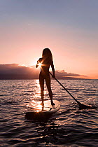 Surf instructor Tara Angioletti at sunset on a stand-up paddle board off Canoe Bearch, Maui, Hawaii. Model released.