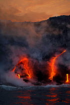 Lava flows into the Pacific Ocean at dawn off the Big Island of Hawaii. Volcanoes National Park, Hawaii.