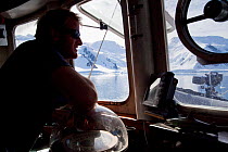 Dion Poncet, skipper, at the bridge of the 'Golden Fleece', base ship for the BBC film crew, passing up the coast of the Antarctic Peninsula, Antarctica, January 2009, Taken on location for BBC Frozen...