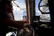 Dion Poncet, skipper, at the bridge of the 'Golden Fleece', base ship for the BBC film crew, passing up the coast of the Antarctic Peninsula, Antarctica, January 2009, Taken on location for BBC Frozen...