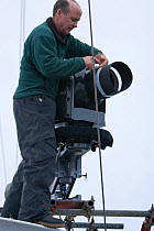 Cameraman, Doug Allan, fixing stabilised high definition film camera on the 'Golden Fleece' (base ship of the BBC film crew) as it passes along the  Antarctic Peninsula, Antarctica, January 2009, Take...