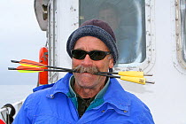 Bob Pitman, scientist, on board the 'Golden Fleece' with Killer whale blubber samplers in his mouth, Antarctica, Taken on location for BBC Frozen Planet series, January 2009