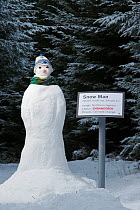 Snow man beside a spoof endangered species sign, Angus, Scotland, UK, January 2010