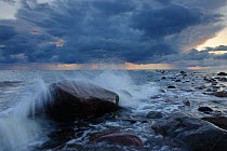 Waves crashing onto beach rock under dark clouds. Hiiumaa Island, Estonia, Europe, August 2011.