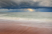 Waves washing up a beach under dark clouds. Hiiumaa Island, Estonia, Europe, August 2011.