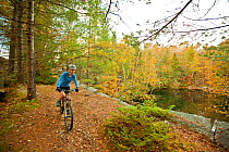 Woman mountain biking on a trail in an abandoned granite quarry on Millstone Hill, Barre, Vermont, USA. autumn. Model released, October 2010