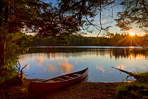 Canoe at sunrise on the shore next to Zack Woods Pond, Hyde Park, Vermont, USA. July 2010