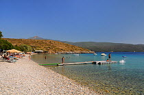 Tourists sunbathing and swimming at Klima beach with the mountains of western Turkey in the background, southeast coast of Samos, Greece, August 2011.