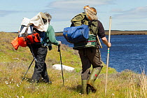 two RSPB scientists carrying equipment for study of aquatic invertebrate adundance as part of Common Scoter (Melanitta nigra) research, Forsinard Flows RSPB reserve, Flow Country, Sutherland, Highland...
