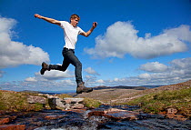 Boy (aged 17) jumping across upland stream, Cairngorms National Park, Highlands, Scotland, UK, August, Model released. 2020VISION Exhibition. 2020VISION Book Plate. Did you know? More than a million p...