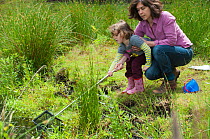 Mother and daughter pond dipping in rhyne at the Westhay Nature Reserve, Somerset Levels, UK, June 2011, model released