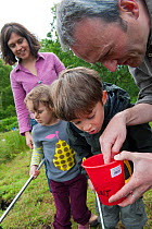 Family pond dipping in rhyne, examining the catch, Westhay Nature Reserve, Somerset Levels, UK, June 2011, model released