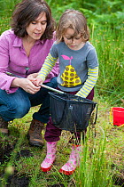Mother and daughter pond dipping in rhyne, visiting the Westhay Nature Reserve, Somerset Levels,  UK, June 2011, model released