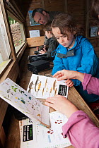 Family looking at identification sheets on visit to the Westhay Nature Reserve, Somerset Levels, UK,  June 2011, model released