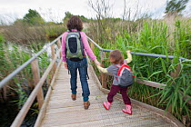Mother and daughter on raised wooden walkway on family visit to the Westhay Nature Reserve, Somerset Levels, UK, June 2011, model released