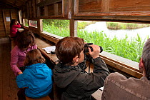 Family birdwatching from hide on visit to the Westhay Nature Reserve, Somerset Levels, UK,  June 2011, model released