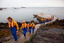Group of tourists wearing waterproof clothing and life jackets landing on Bass Rock, North Berwick, Firth of Forth, Lothian, Scotland, UK, August 2011