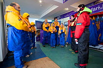 Group of tourists wearing waterproof clothing and life jackets preparing for zodiac boat tour to Bass Rock, North Berwick, Firth of Forth, Lothian, Scotland, UK, August 2011