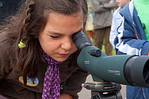 Girl looking down telescope at seabirds at Scottish Seabird Centre, North Berwick, Firth of Forth, Lothian, Scotland, UK, August 2011