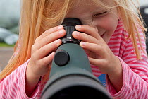 Young girl looking down telescope at seabirds at Scottish Seabird Centre, North Berwick, Firth of Forth, Lothian, Scotland, UK, August 2011. 2020VISION Book Plate.