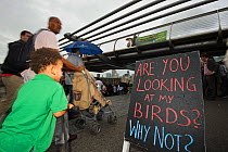 People walking past a sign advertising the RSPB 'Date With Nature Event' for learning about urban Peregrine falcon, Tate Modern, South Bank, London, UK, September 2011, RSPB Greater Thames Futurescape...