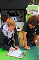 Young woman signing up for  RSPB membership with staff member Murray Wrathmell at RSPB 'Date With Nature Event' for learning about urban Peregrine falcon, Tate Modern, South Bank, London, UK, September 2011, RSPB Greater Thames Futurescapes Project. Model released.