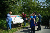 Hikers read information board on the Red Kite trail in the Urban Red Kite area of the Derwent Valley, Gateshead, Tyne and Wear, UK, on the edge of Tyneside following on from the 'Northern Kites' re-in...