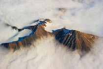 Aerial photo of mountain peaks and cirques through cloud layer. Spitsbergen, Svalbard, July.