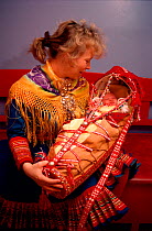 Sami mother with her baby in traditional cradle at christening. Kautokeino, Norway.